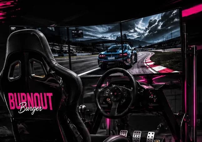 Rennsimulator mit drei Bildschirmen und rosa Sitz mit Burnout-Burger-Schriftzug